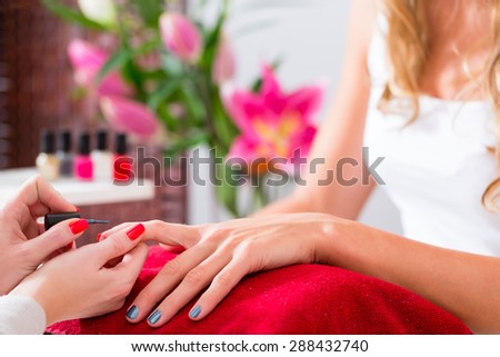 Woman receiving manicure in beauty parlor, her nails being polished