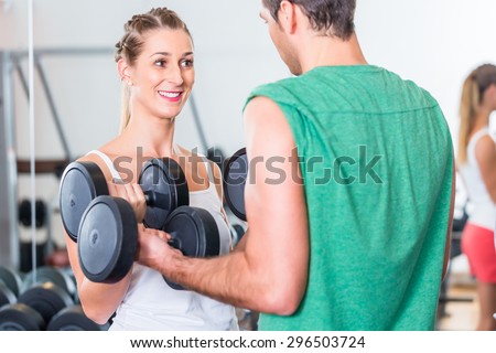 young couple in gym lifting dumbbells in fitness exercise workout
