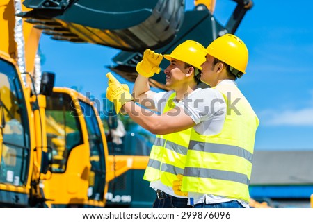 Asian worker at construction machinery of construction site or mining company