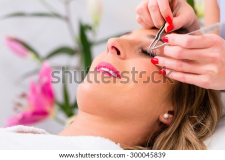 Woman receiving false eye lashes in beauty studio