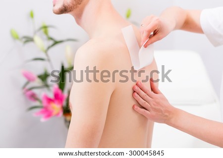 man receiving waxing for hair removal in beauty parlor