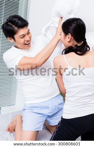 Chinese Woman and man having pillow fight