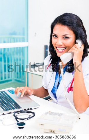 Asian female doctor working and telephoning in office or medical practice