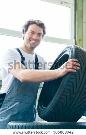 Auto mechanic changing tire in car workshop
