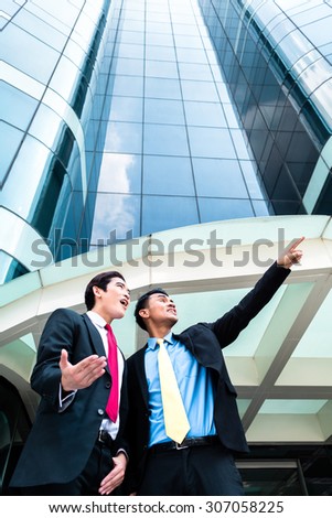 Asian business men outside in front of tower building