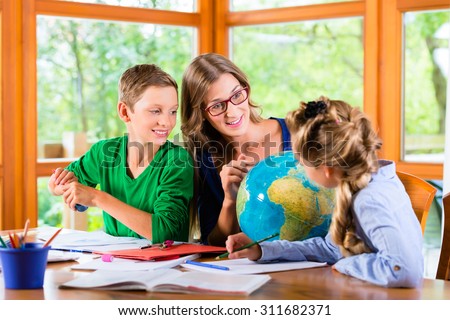 mom holding a globe showing countries to her children