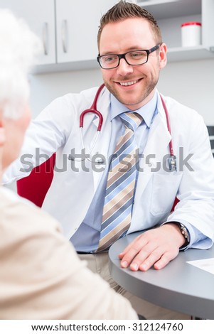 Doctor sitting with pensioner in surgery consultation hour at desk