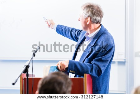 College professor giving lecture for students standing at desk