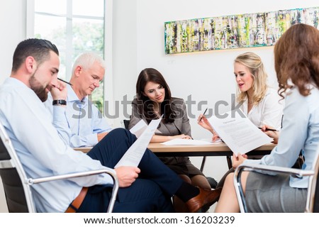 Lawyers having team meeting in law firm reading documents