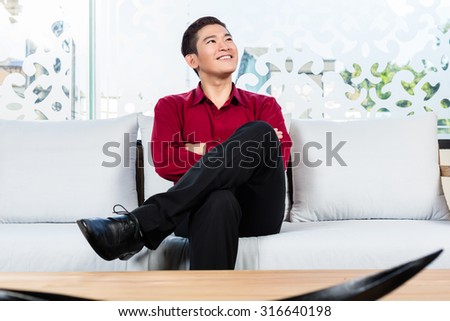 Asian Korean man sitting on sofa in furniture store