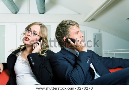 Two business people talking to their phones looking in different directions