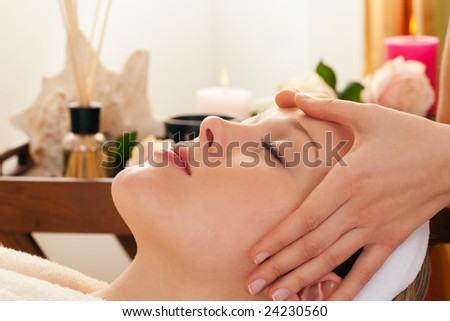 Beautiful woman enjoying a face massage competently carried out in a spa - in the background lots of accessories