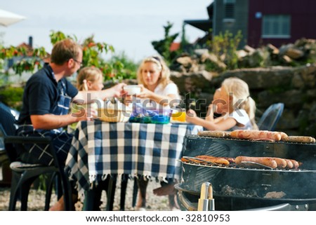 Family having a barbecue in the garden, eating (focus on barbeque grill!)
