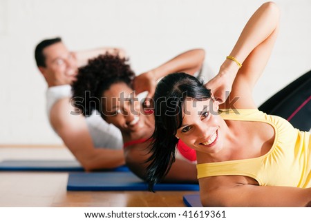 Group of three people exercising doing sit-ups in the gym