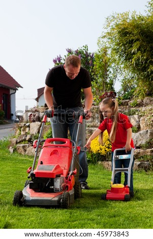 Father and Child mowing the lawn together, daddy has a real lawnmower, the daughter a toy version and is a bit jealous