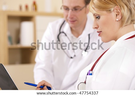 Two doctors - male and female - discussing documents in their practice, test reports or maybe administrative stuff