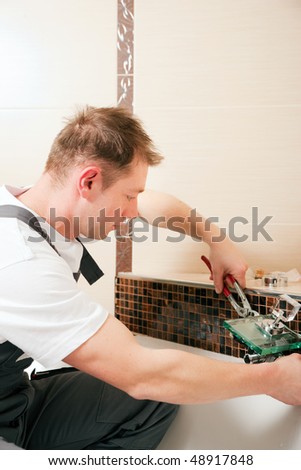 Plumber installing a mixer tap in a bathroom, he is sitting in the bathtub, focus on eyes of the man!