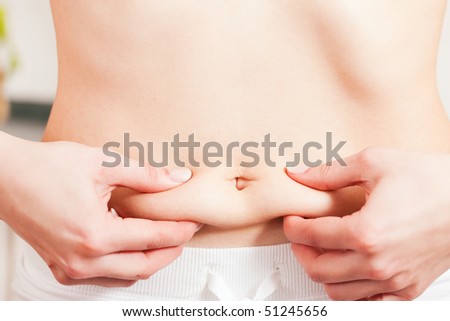 Woman is grabbing her love handles being not too satisfied with their status after a long winter - she will have to loose some weight