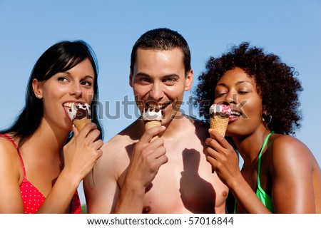 Group of friends - one man and two women eating ice cream in swimwear and bikini, it seems to be a hot summer day