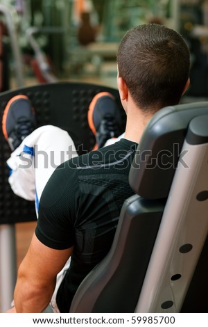 Man doing fitness training on leg press with weights in a gym