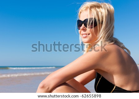 Attractive Woman in monokini standing in the sun on beach, only one half to be seen, a lot of copyspace in the blue sky