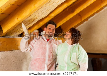 Couple installing thermal insulation thru glass wool on their roof, they are looking pretty proud