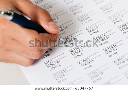 Man (only hand to be seen, presumably an accountant) working on a document with numbers