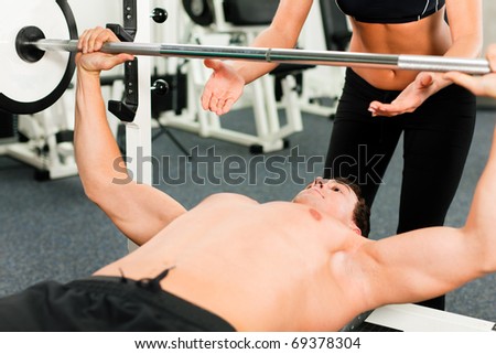 man in gym with personal fitness trainer exercising power gymnastics with a barbell