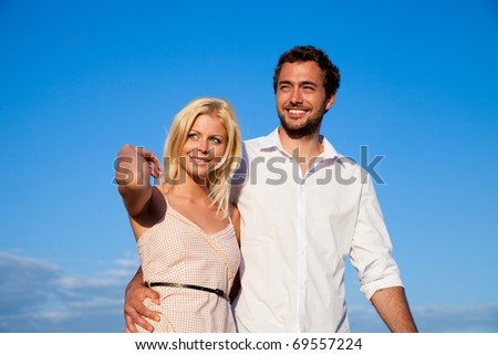 Couple in vacation having a walk under a perfect blue sky, they are embracing each other on shoulder