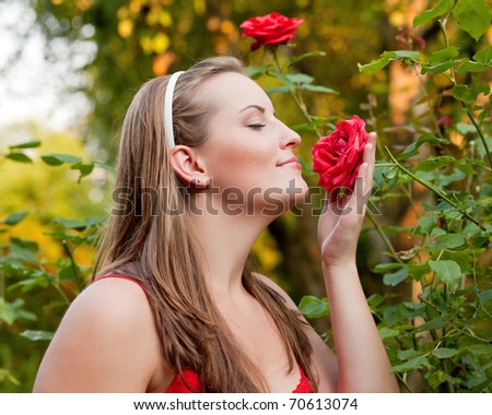 Woman doing garden work sniffing at the roses at beautifully sunny day