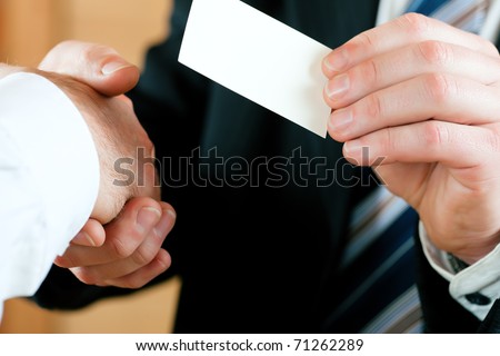 Businessmen having handshake, one handing business card over; only hands to be seen