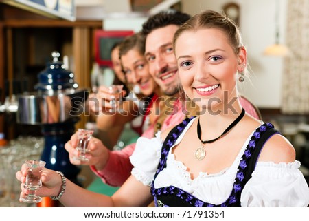 People in Bavarian Tracht drinking hard liquor in a pub and have fun