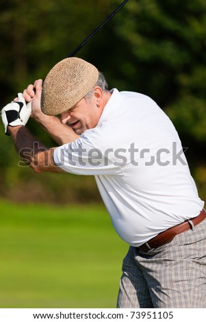 Senior golfer only torso to be seen - doing a golf stroke, he is playing on a wonderful summer afternoon
