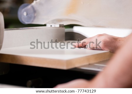 Carpenter - only hands to be seen - working on an electric buzz saw cutting some boards