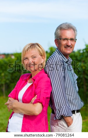 Visibly happy mature or senior couple outdoors back to back having a walk