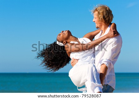Happy couple - black woman and Caucasian man - at the beach in their vacation