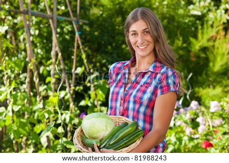 Gardening in summer - happy woman with freshly harvested vegetables