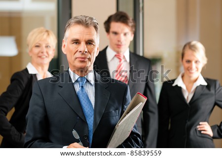 Business - team in an office; the senior executive is standing in front
