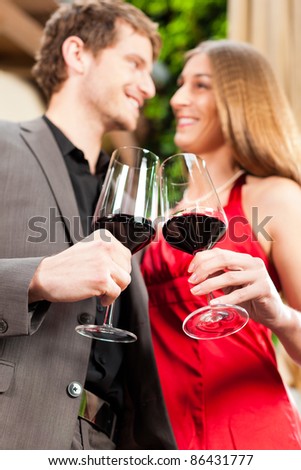 Couple, man and woman, at wine tasting in a restaurant, each with glass of red wine in hand