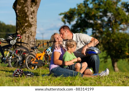 Happy family (father, mother and son) on getaway with bikes - they have a break