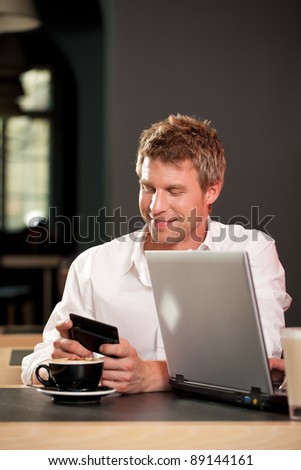 Couple in coffee shop with laptop and mobile; only the man is to be seen
