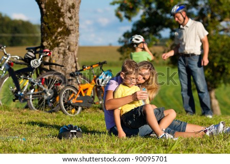 Happy family (father, mother and two sons) on getaway with bikes - they have a break