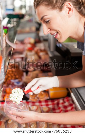 Smiling female butcher packing delicious meal at shop