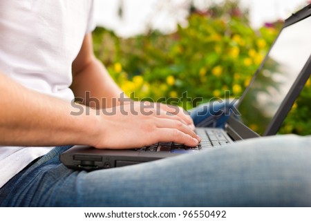 Man - only torso - is working on his laptop outdoors; presumably it is his garden