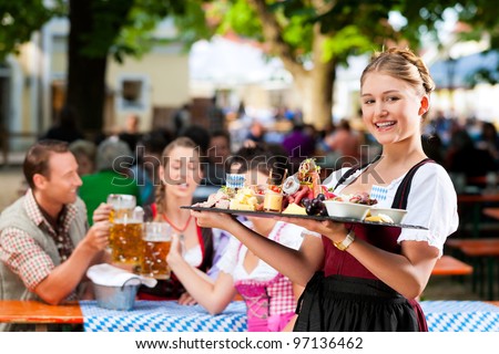 Beer garden restaurant in Bavaria, Germany - beer and snacks are served, the waitress also wears traditional costume