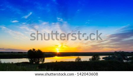Sunrise over fields and a lake sun