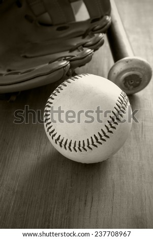 Old well used baseball with mitt and bat in black and white sepia tint