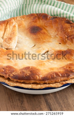 Home baked pie with a golden puff pastry crust baked in enamelware pie dish can be used for savory or sweet fillings