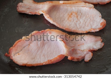 Back or middle bacon frying in a pan a traditional cut from the loin and belly