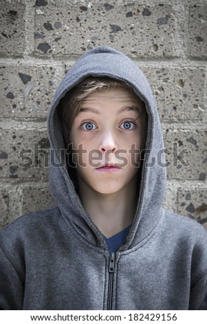 portrait of a male teenager with wide eyed in front of a wall.